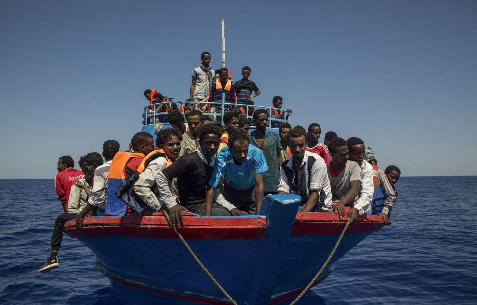 Foto: Angelos Tzortzinis, Agence France-Presse. Dei migranti attendono i soccorsi sulla loro fragile imbarcazione, in pieno Mar Mediterraneo